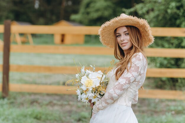 A beautiful young bride with a bouquet of daisies in a field