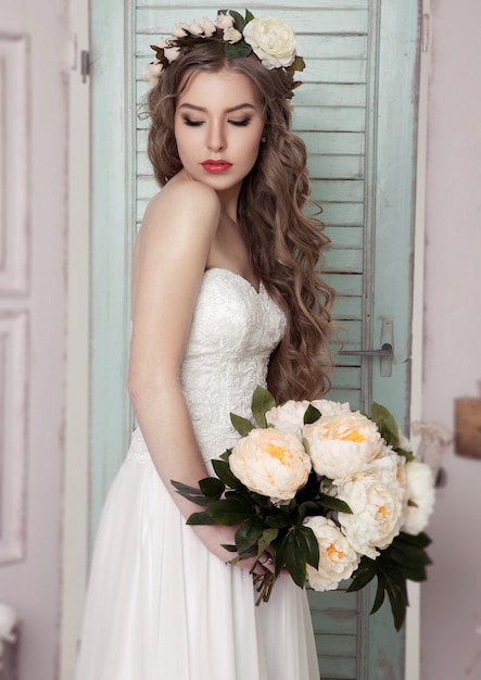 Beautiful young bride with crown flowers and romantic decoration pink and green. Wooden boxes bottles and different wedding decoration