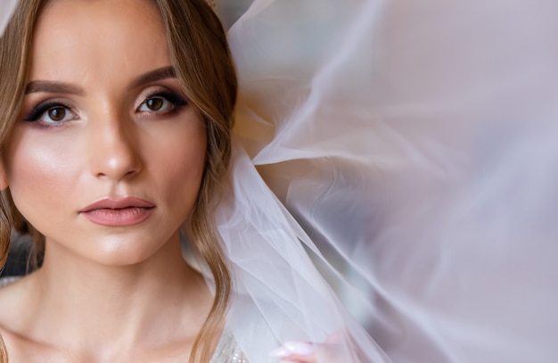 Foto bella giovane sposa con trucco sposa e acconciatura in camera da letto. ritratto di bella sposa con velo