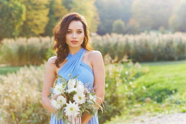 Beautiful young bridesmaid with curly hair posing on wedding ceremony