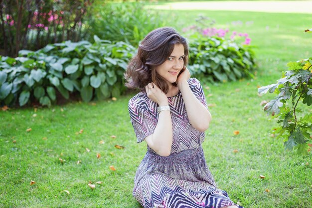 Beautiful young brunete woman resting and smiling on park or garden green background