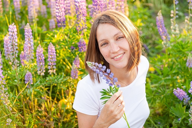 Beautiful young brunete woman resting on summer field with blooming wild flowers green background