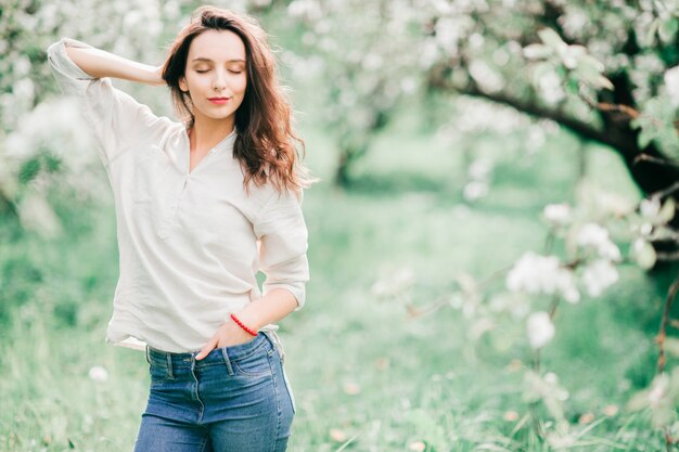 Beautiful young brunette enjoying in emerald summer park with her eyes closed