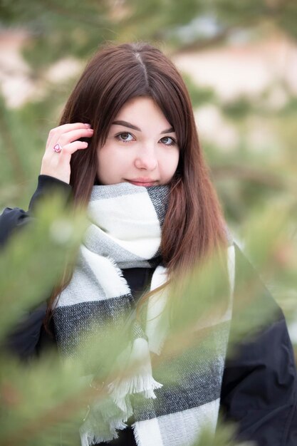 Beautiful young brunette girl on the background of fir branches