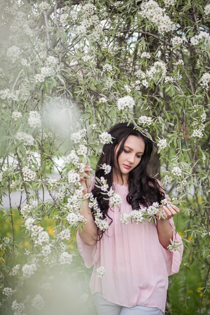 Foto bella giovane ragazza castana che posa in un giardino di fioritura
