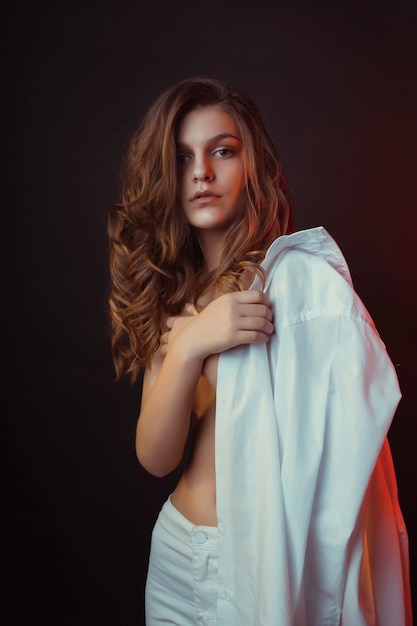 Beautiful  young brunette lady posing in men's shirt at studio