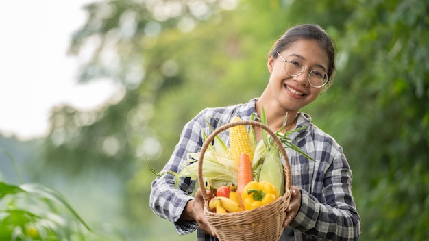 緑の竹かごに野菜を持っている美しい若いブルネットの肖像画の有名な女性の手