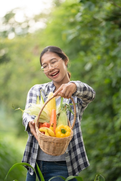 緑の竹かごに野菜を持っている美しい若いブルネットの肖像画の有名な女性の手