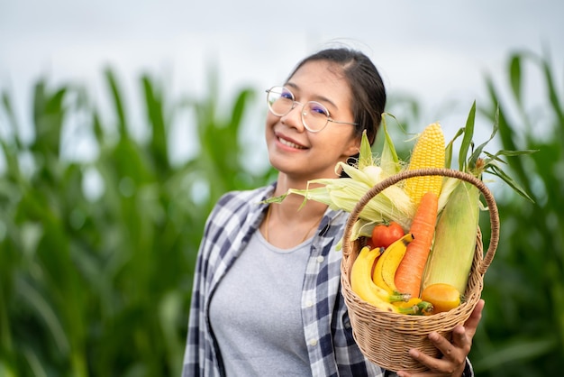 緑の竹かごに野菜を持っている美しい若いブルネットの肖像画の有名な女性の手