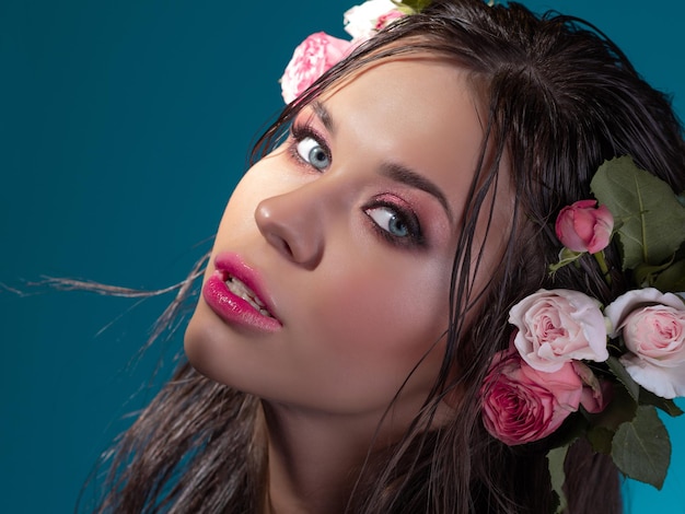 A beautiful young brunette with bright blue eyes in a hawaiian image wet hair and flowers in the hai...