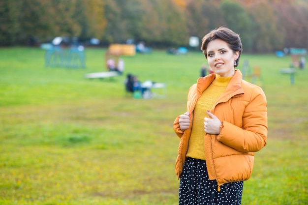 Beautiful young brunette woman posing in a yellow knitted sweater and jacket against the background