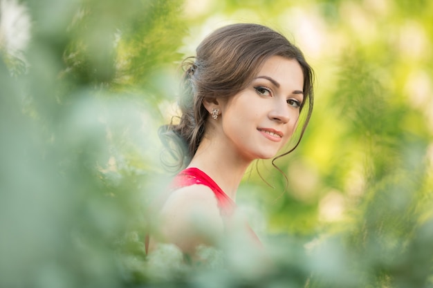 Beautiful young brunette woman standing near white blossom