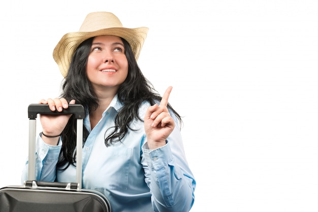 Шляпа красивой молодой женщины брюнет нося при чемодан изолированный на белизне.