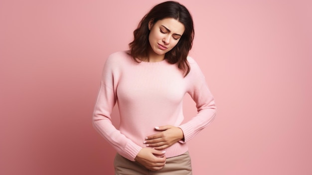 beautiful young brunette woman wearing sweater suffers from stomachache isolated on pink background