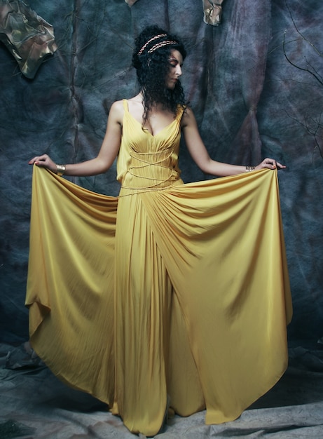 Beautiful young brunette woman wearing yellow evening dress