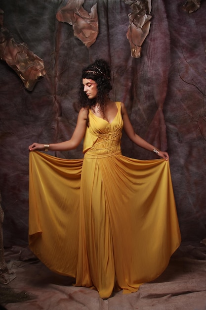 Photo beautiful young brunette woman wearing yellow evening dress