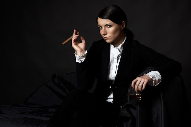 Beautiful young brunette woman with cigare in suit