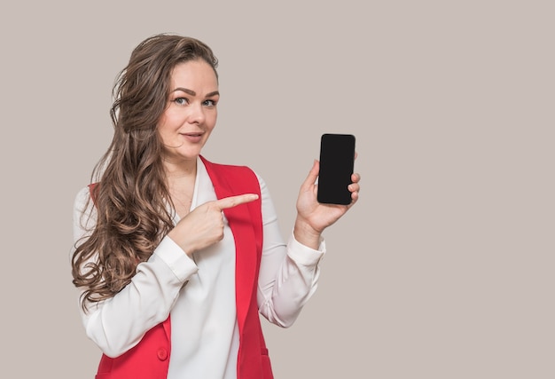 Beautiful young brunette woman with long hair in a red jacket with a phone in her hands.