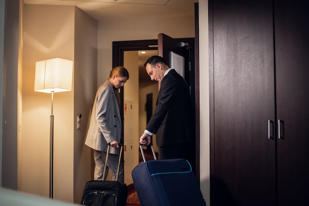 A beautiful young business couple leaving their hotel room with the suitcases