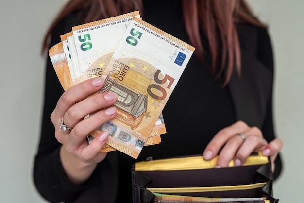 Beautiful young business lady in stylish clothes holding a big\
purse with euro banknotes. full wallet concept