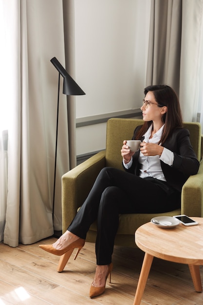 beautiful young business woman in formal wear clothes indoors at home drinking coffee.