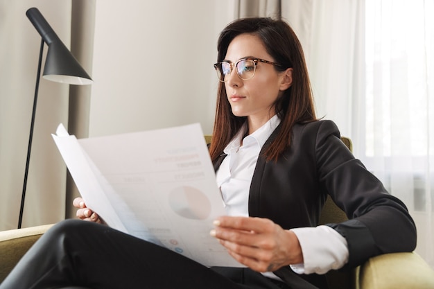 beautiful young business woman in formal wear clothes indoors at home work with documents and graphics.