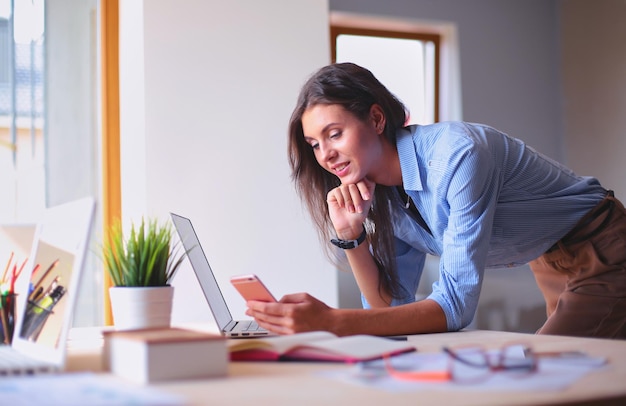 Beautiful young business woman sitting at office desk and talking on cell phone Business woman