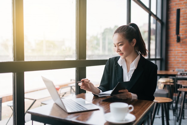 Beautiful young business woman sitting at table and taking notes