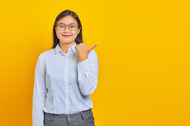 Beautiful young business woman smiling with confident face pointing to empty space with finger