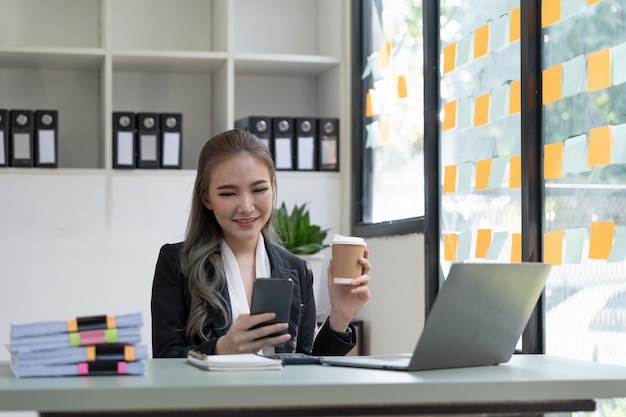 Beautiful young business woman using phone in office