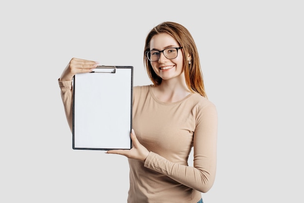 Beautiful young business woman wearing glasses holds a clipboard