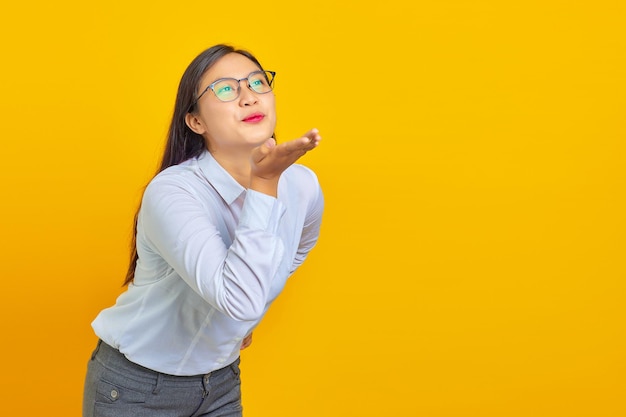 Beautiful young business woman with confident face holding palms sending air kiss to boyfriend