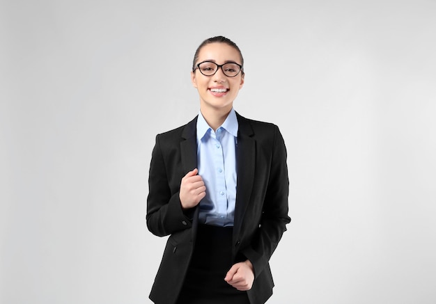 Beautiful young businesswoman in elegant suit on light background