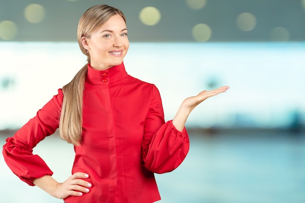 Beautiful young businesswoman pointing at copy space isolated