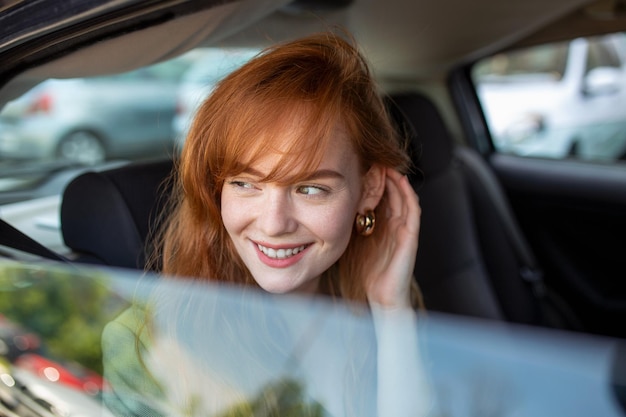 車の後部座席に座って窓の外を見ている美しい若いビジネスウーマンタクシーで旅行する女性ビジネスエグゼクティブ