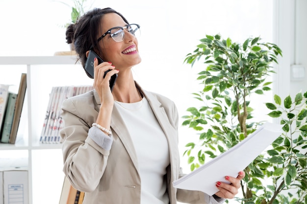 Beautiful young businesswoman using her mobile phone in the office.