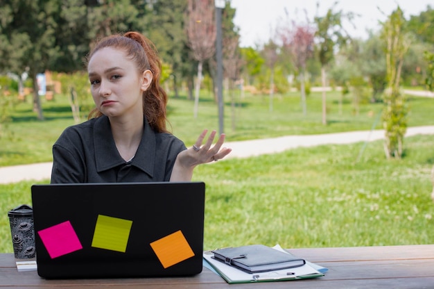 Beautiful young businesswoman working outside looking at camera asking