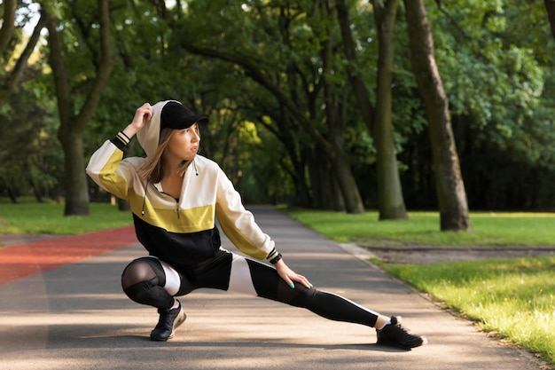 Beautiful young caucasian woman in fitness wear working out in a park.