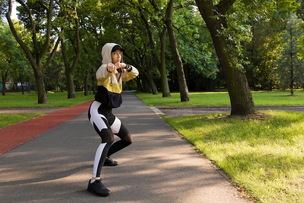 Beautiful young caucasian woman in fitness wear working out in a park.