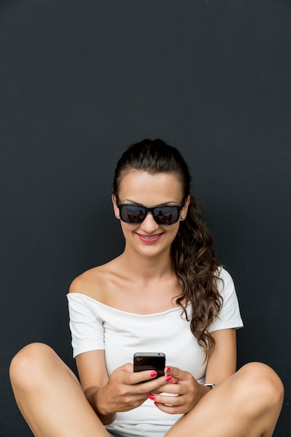 Beautiful young caucasian woman with smartphone, texting. Happy teenage girl with brunette hair.