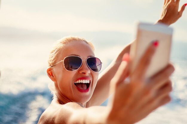 Beautiful young cheerful woman taking a selfie while enjoying on a cruise.