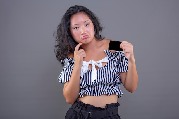 Beautiful young chinese woman with card in hand and graceful expression of hesitation