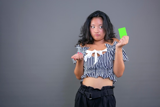 Beautiful young chinese woman with card in hand and graceful expression of hesitation