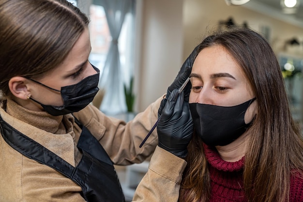 A beautiful young client in a special black mask came to the\
salon for makeup during a pandemic. the concept of beauty services\
during a pandemic