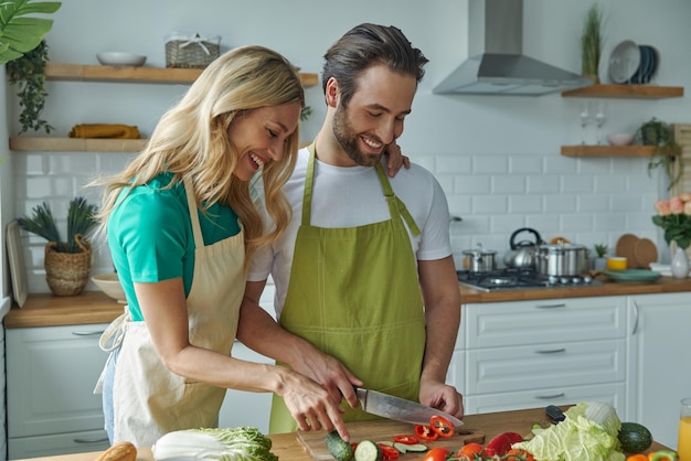 Photo beautiful young couple bonding while cooking together at the domestic kitchen