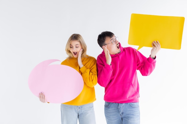 Beautiful young couple in casual clothes is holding colorful speech bubbles