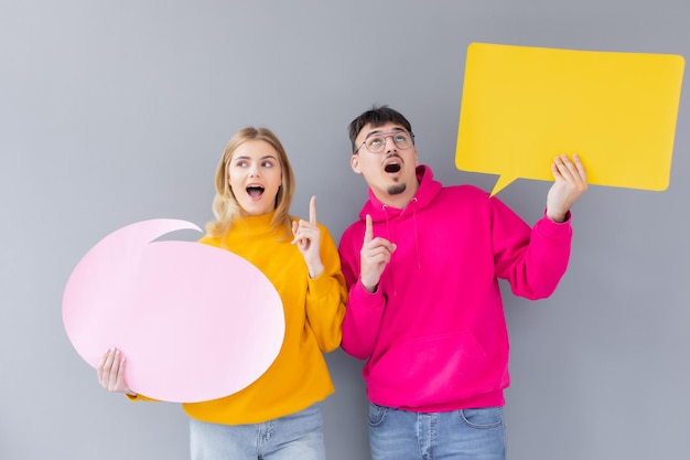 Beautiful young couple in casual clothes is holding colorful speech bubbles