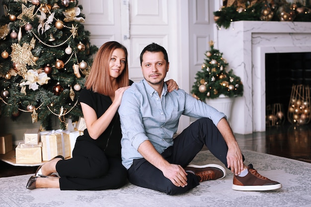 Photo beautiful young couple next to the christmas tree