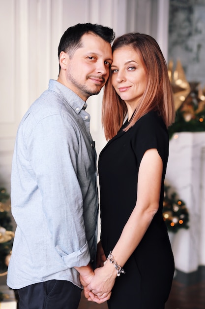 Foto bella giovane coppia a natale. una giovane donna e un uomo sorridono e si divertono insieme.