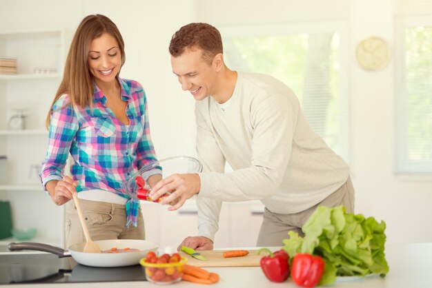 Beautiful young couple cooking healthy meal in the domestic kitchen.